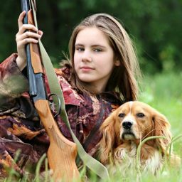 woman with a hunting rifle and dog