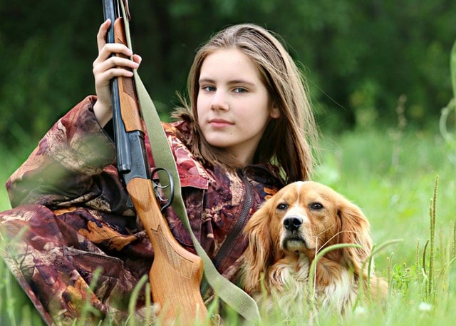 woman with a hunting rifle and dog