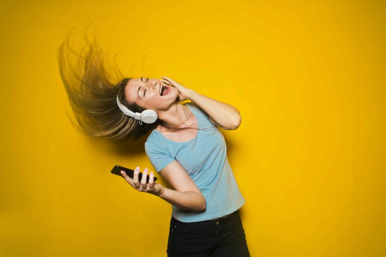woman listening to music in headphones while whipping her hair back and forth