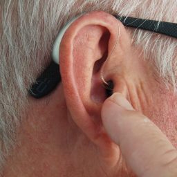 Man touching his hearing aid with his finger while it's in his ear