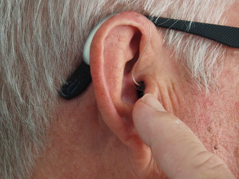 Man touching his hearing aid with his finger while it's in his ear