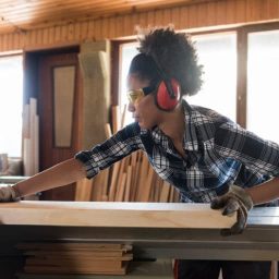Woman using a table saw with hearing protection on