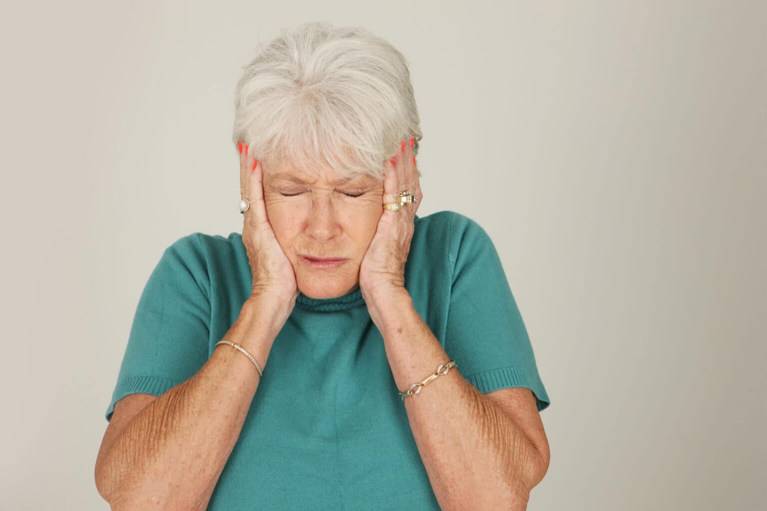 Older woman putting hands over her ears.