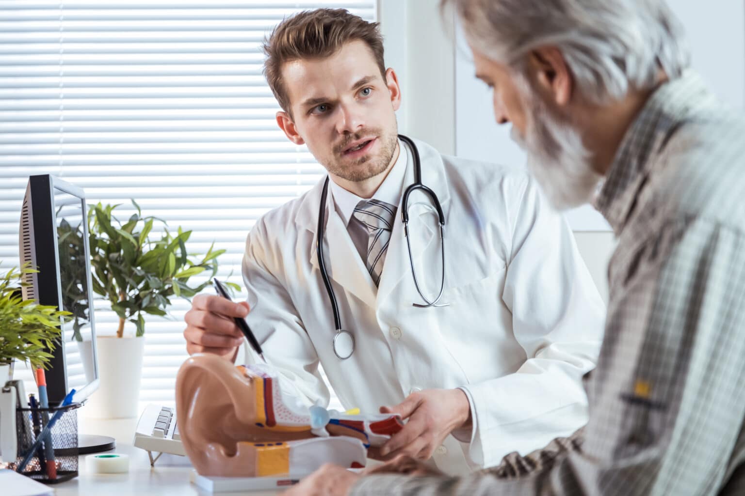 Audiologist talking to a senior male patient about hearing loss.