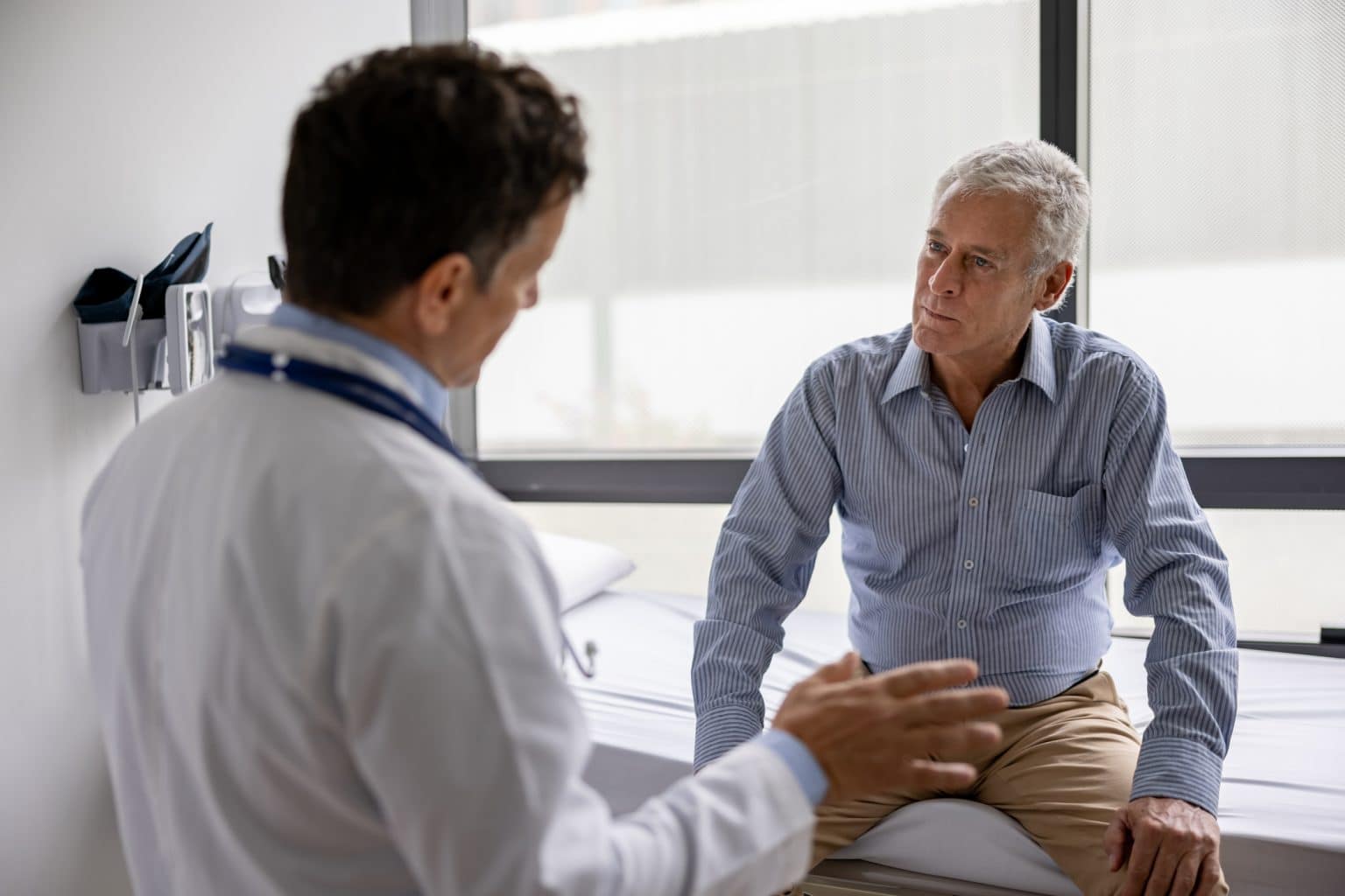 Doctor talking to a patient in a consultaton at his office practice - healthcare and medicine concepts