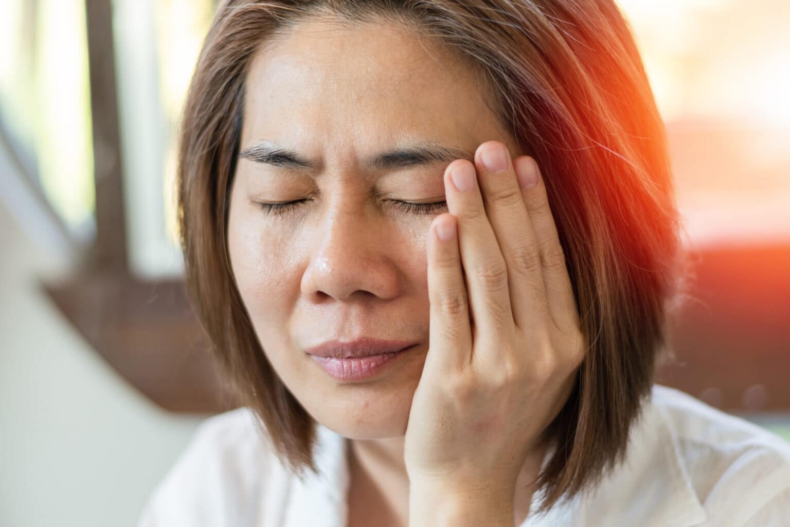 close-up image of a woman putting her head in her hands