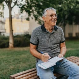 Happy man sitting on a bench working on his 2025 resolutions