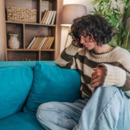 Woman sitting on a couch holding her pounding head