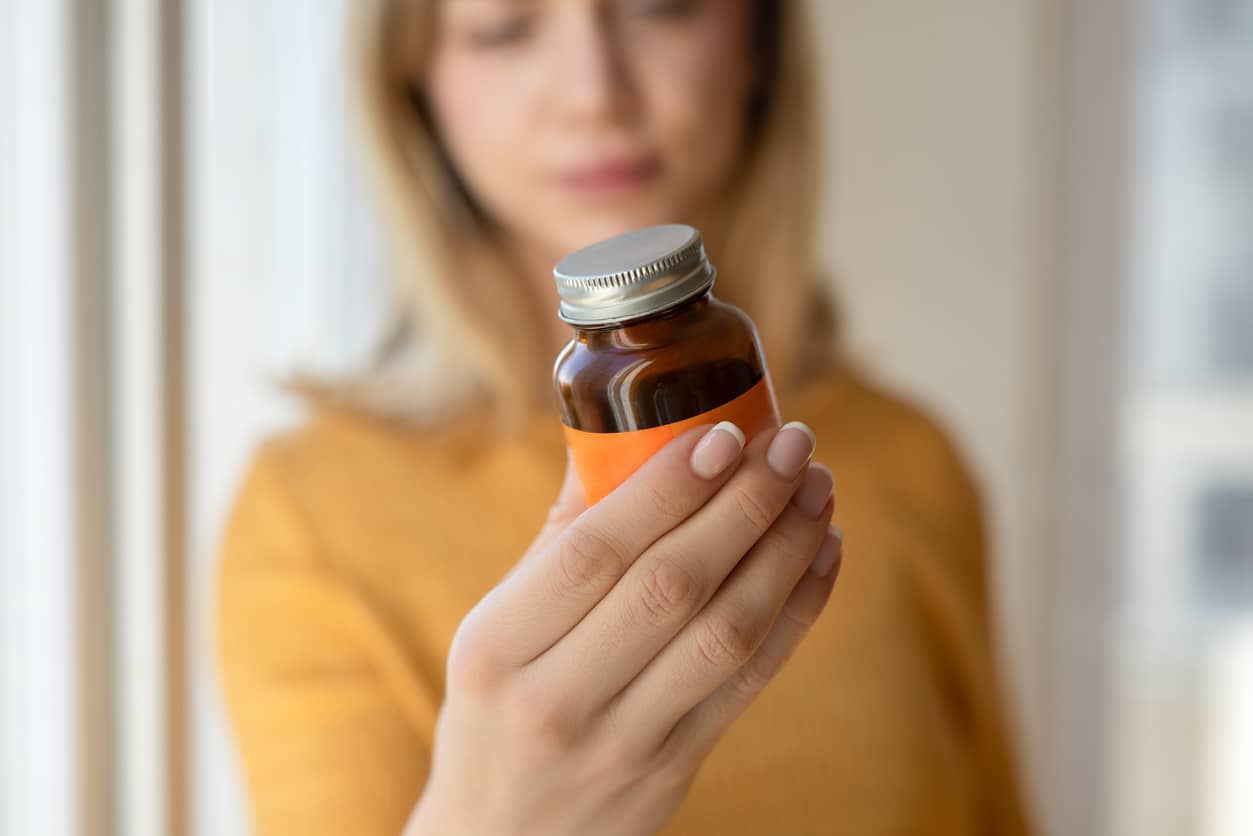 Woman holding supplement bottle.