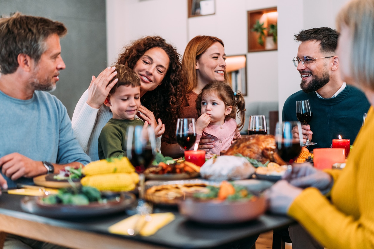 Happy extended family celebrating Thanksgiving at dining table.